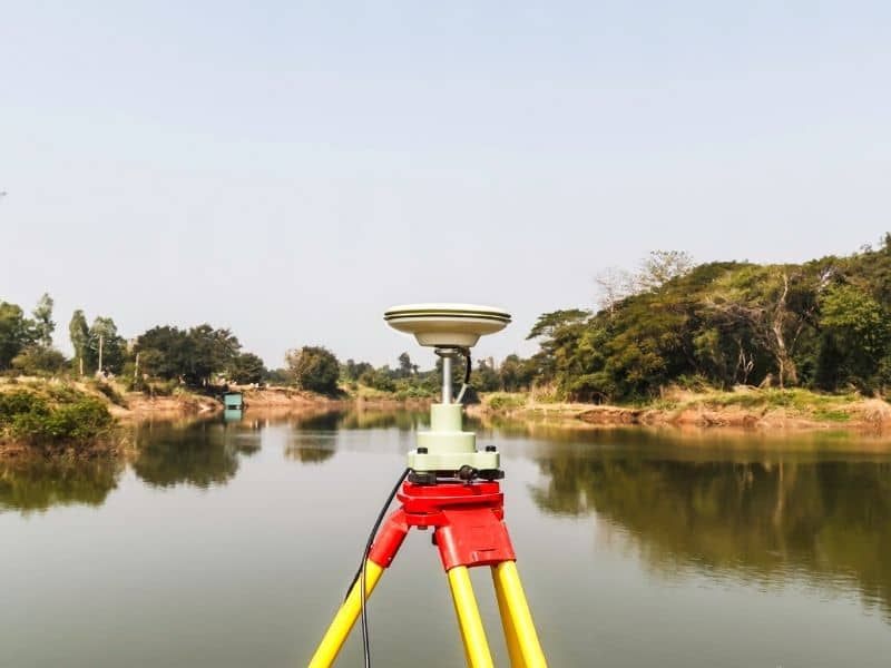 GPS surveying equipment used near a creek boundary during a metes and bounds survey in Daphne, Alabama.