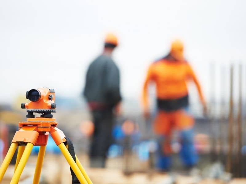 Land surveyor measuring multiple structures including a house, barn, shed, pool, and driveway on a residential property.
